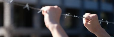 Hand behind barbed wire in prison or slavery. Punishment and imprisonment concept