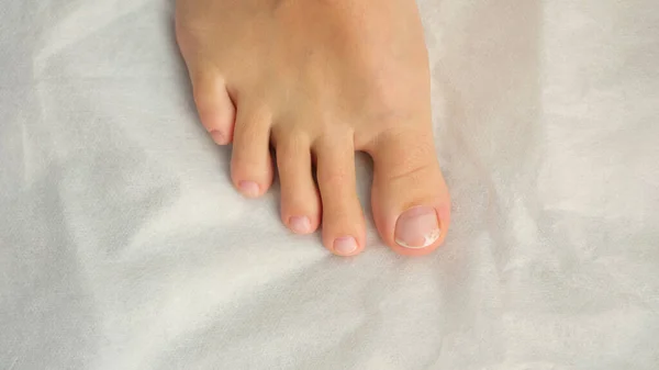 Close-up of female foot with pedicure, cosmetic treatment of feet and toenails. Podology, fungus treatment and beauty concept