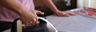 Woman with iron in hands irons clothes on ironing board. Housework and cleaning. Distribution of duties.