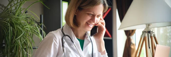 Leende Kvinnlig Läkare Talar Telefon Arbetsplatsen Kliniken Remote Consultation Patients — Stockfoto