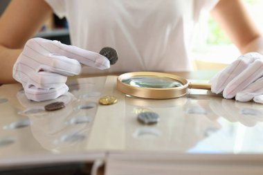 Kadın numismatist madeni para koleksiyonunu inceliyor. Kadın büyüteçten bozuk paralara bakıyor. Numismatic koleksiyon incelemesi.