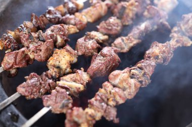 Preparation of shish kebab bbq. Close-up shot of meat skewers in barbecue picnic on open fire. clipart