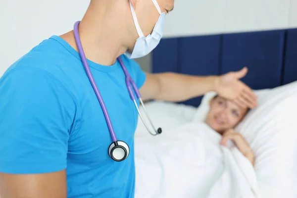 病気の女性の額に触れる男開業医の肖像 患者の検討 病気の女性が悪い 医療の概念 — ストック写真