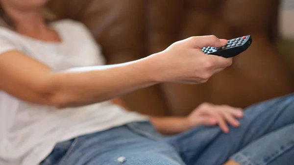 stock image Close-up of woman holding tv remote control and surfing programs on tv. Watching TV and home entertainment concept