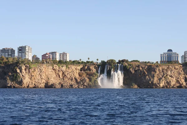 Sea view of waterfall and coastline with hotels and buildings. Panoramic view of sea resort from yacht.