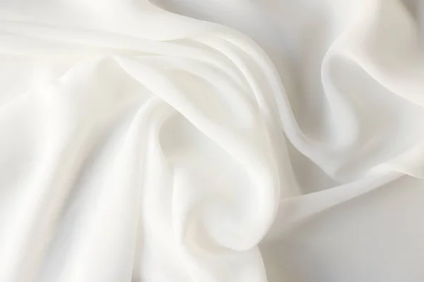 White satin background or design element. Wavy white silk fabric close up.