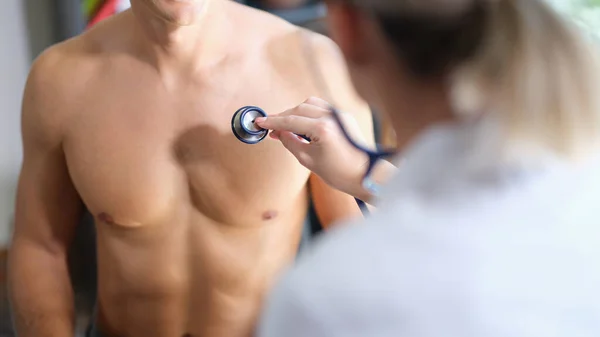 女医は診療所で男性患者を診察する 聴診器に焦点を当てました ヘルスケアの概念 — ストック写真