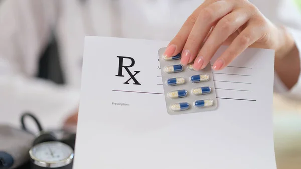 女性医師は薬と処方紙のパッケージを手に持っている 薬剤師の手によるブランク処方クローズアップ — ストック写真