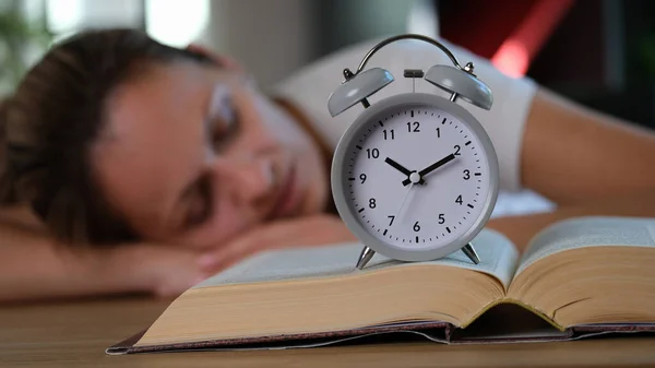 수없는 두꺼운 책에는 시계가 있으며 여자는 뒤에서 연구와 불면증의 — 스톡 사진