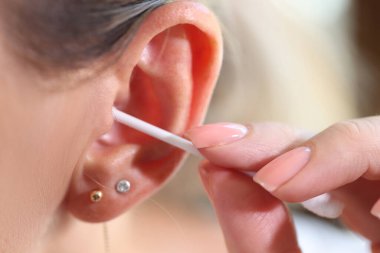 Close up of women cleans her ear with cotton swab. Hygiene of people and body care concept.