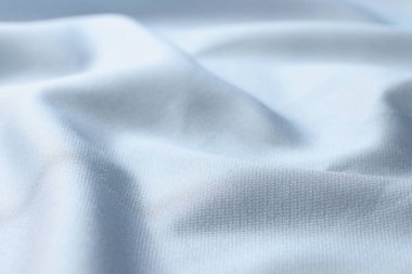 Waved light blue silk fabric background. Close up of light satin textile.