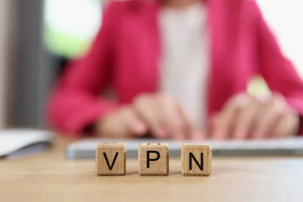 Letters VPN on wooden cubes - Virtual Private Network and Internet user works on computer in background. VPN service for secure, encrypted connection and anonymously on Internet.