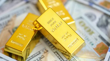Close up of gold bars on many US dollar bills. Gold trading, exchange rates and saving money concept.