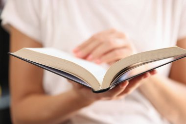 Open book in hands of woman close-up, shallow depth of field. Concept of education, learning and knowledge.