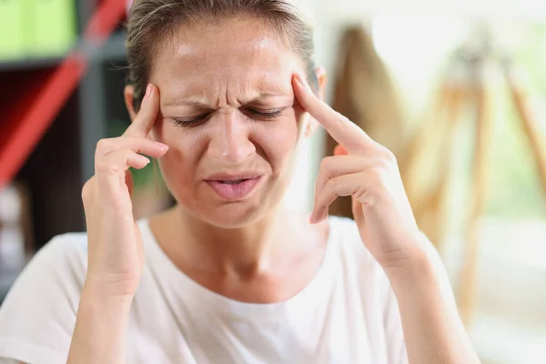 Sad and tired woman with hands touching her forehead suffering from headache, migraine or depression. Upset frustrated woman with many problems and stress closeup.