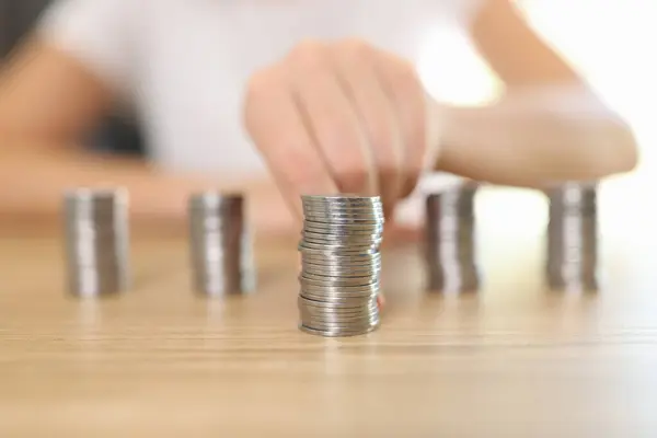 stock image Womans hand lays out piles of coins on wooden table. Concept of budget management, savings and investment.