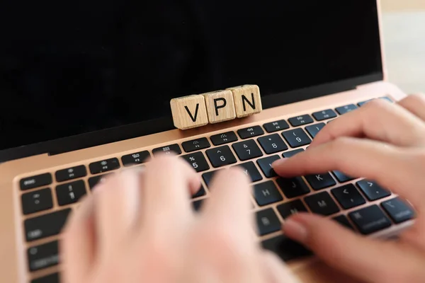 Hands User typing on laptop keyboard with word VPN on wooden cubes close up. Virtual Private Network for secure and encrypted internet connection and anonymously.