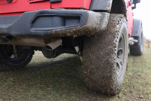 Dirty wheels of red offroad car close-up. Extreme adventures and travel trip concept.