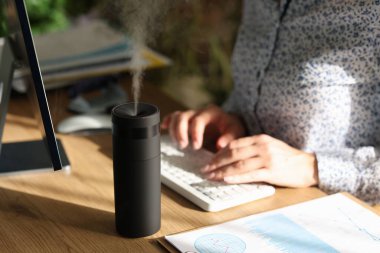 Humidifier on the desk of an office worker, close-up. Modern household appliances, ionizer