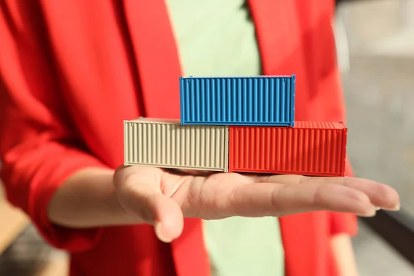 A business woman holds in the palm of the cubes of containers, a close-up. Cargo transportation and logistics