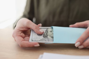 Female hands get a pack of dollars from an envelope, close-up. Concepts criminal money, bribe, exchange