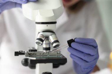 Close-up of chemist lab assistant looking at test sample using microscope. Quality control and laboratory research concept