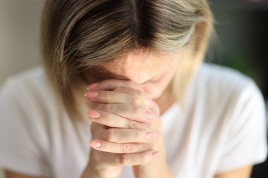 Close-up of praying woman folded hands, tilting head and prays. Faith, spirituality and religion concept