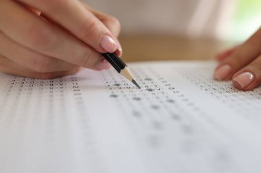 Close-up of woman solving tests and writing with pencil on paper. Exam testing concept