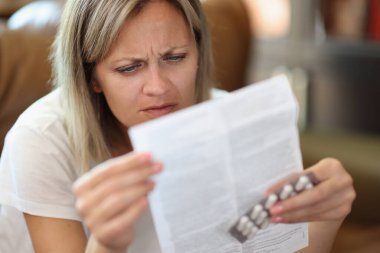 Portrait of serious woman reading instructions for medical use of medicines. Healthcare, treatment and medicine concept