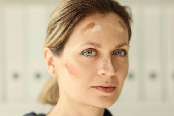 Skin tone cream lines on woman face close up. Makeup and skin care concept.