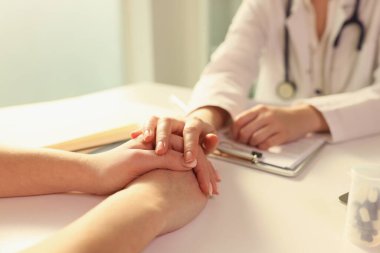 Doktor elini hastanın ellerine koydu, onunla klinikte oturuyordu. Ameliyattan önce hastalara destek ve empati.