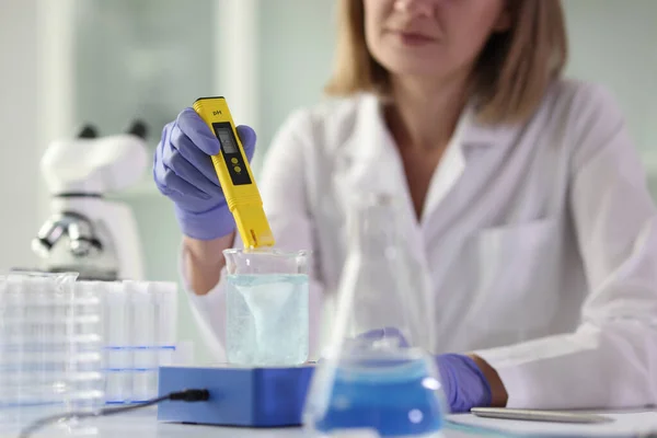 女性科学者は科学研究室で研究を行う フラスコ 試験管 顕微鏡を備えた化学者がテーブルに座っています — ストック写真
