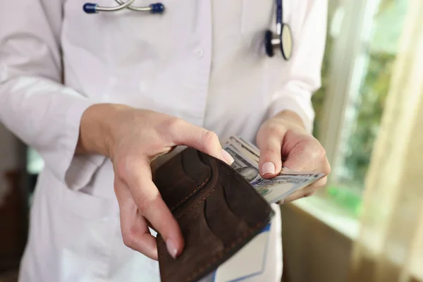 Female doctor hides money in wallet in hospital. Crime, bribery and salary of doctors and nurses.