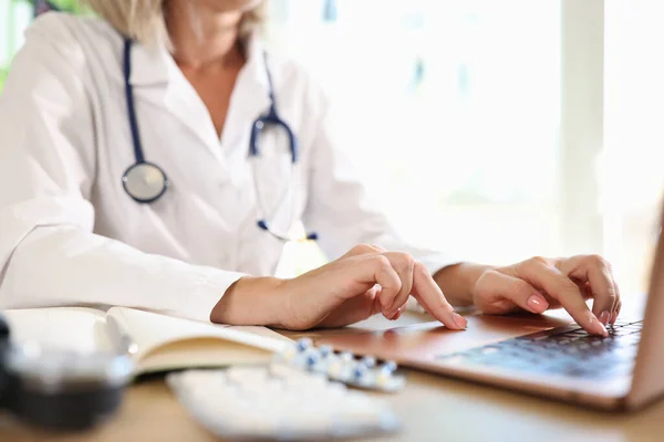 女医は病院のノートパソコンで働いていて テーブルに座っている オンライン相談 遠隔医療 医療書類の概念 — ストック写真