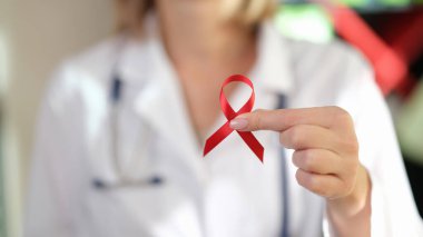 Kadın doktorun elinde Uluslararası AIDS Günü 'nün sembolü olarak kırmızı kurdele var. HIV farkındalığı..