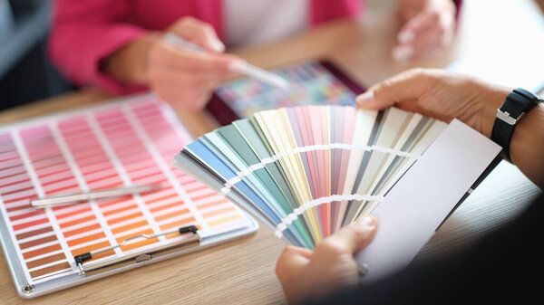 Designer and her client choosing colors for home renovation. Design studio concept, two people and lots of color swatches.