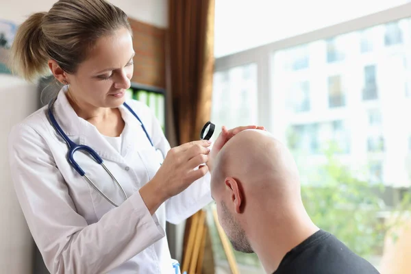 Vänlig Kvinnlig Läkare Med Förstoringsglas Tittar Huvud Hud Manliga Patienten — Stockfoto