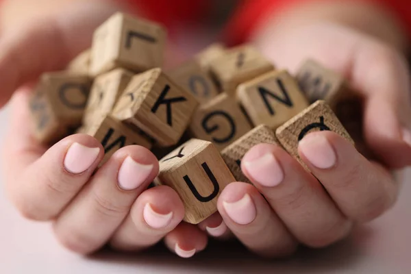 Many symbols of alphabet in hands of woman close-up. Languages, creativity and learning concept.
