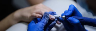 Close-up of manicurist doing manicure to client using special apparatus, hardware manicure. Beauty day and body care concept