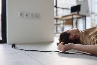 Kadın, elektrik şokuna maruz kalmış bir şekilde ofiste yerde yatıyor. Kadın çalışan, elektrik teçhizatının uygunsuz kullanımı nedeniyle zarar gördü