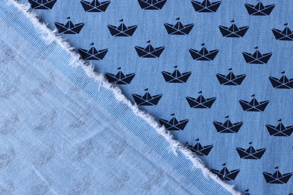 Blue cotton fabric with ships pattern for children clothes upper view. Folded textile material with small ornament. Sewing industry