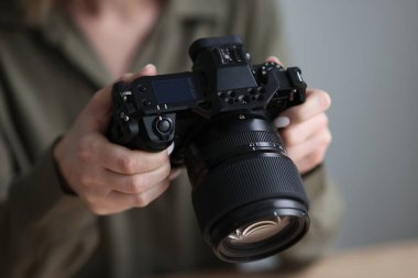 Profesyonel fotoğrafçı elinde büyük mercekli kamerayla mankenin çekilen fotoğraflarını kontrol ediyor. Çalışma için modern fotoğrafçılık ekipmanları