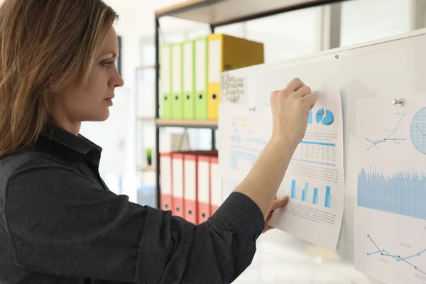 stock image Woman puts paper with infographic charts on board preparing for business presentation in office closeup. Manager performs visual materials