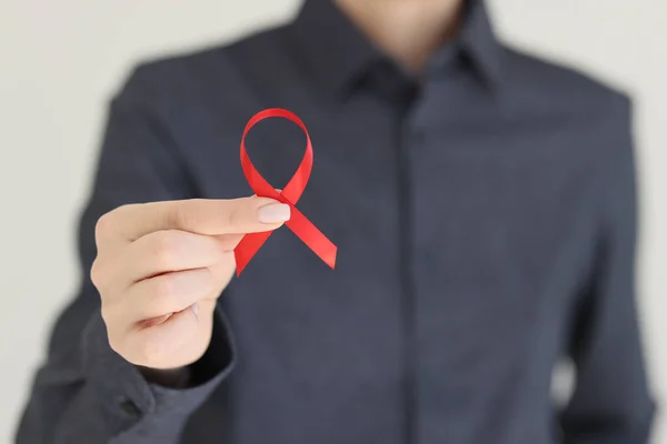 Woman holds red ribbon representing fight against AIDS. Symbol of awareness and solidarity with HIV-positive people and persons living with AIDS