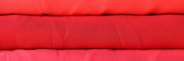 ニット生地の質感の背景の赤いロールのクローズアップ 赤の背景の異なる色の色合いを持つ布 — ストック写真