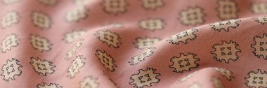 Dikiş için baskısı olan pembe pastel ipek kumaşın üst görüntüsü. Moda koleksiyonu için nefis bir kumaş. Şık, dalgalı ipek ya da keten deseni