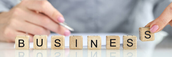 Close-up of businesswoman collected business word with wooden cubes. Time management, marketing and business concept