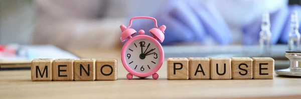 stock image Close-up of word menopause collected of wooden cubes in raw and pink alarm-clock. Gynecology, women health and healthcare concept