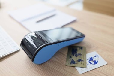 Kredi kartları ofisteki e-ödeme terminalinin yanındaki ahşap masada duruyor. Çevrimiçi hizmetler için büyük paralar kazanmak için modern bankacılık ekipmanları