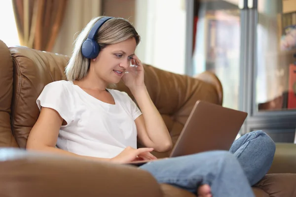 Fair Haired Woman Works Laptop Listens Music Headphones Sitting Comfortable — Stock Photo, Image